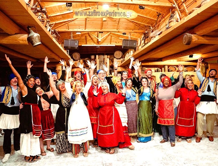 America Greece Tours travelers enjoying a traditional Greek night in Athens with live music, folk costumes, dancing, and authentic Greek cultural entertainment.